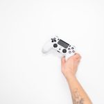 Hand greift zu einem Game-Controller vor weißem Hintergrund